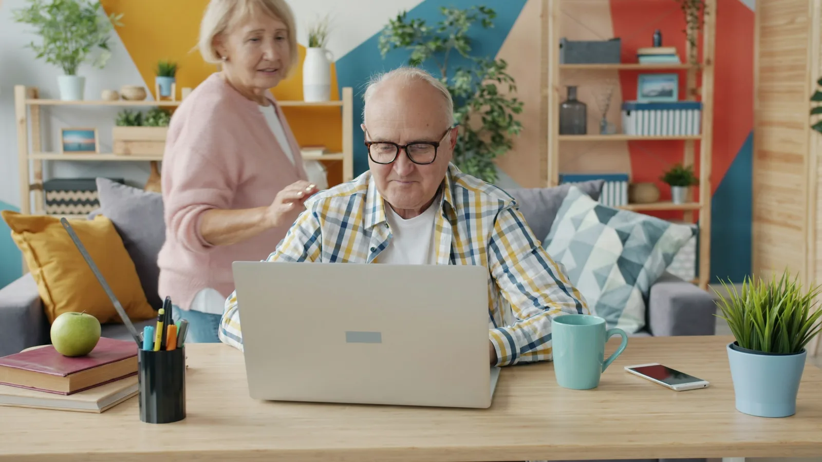 Ein älteres Paar sitzt im Wohnzimmer gemeinsam vor einem Laptop.