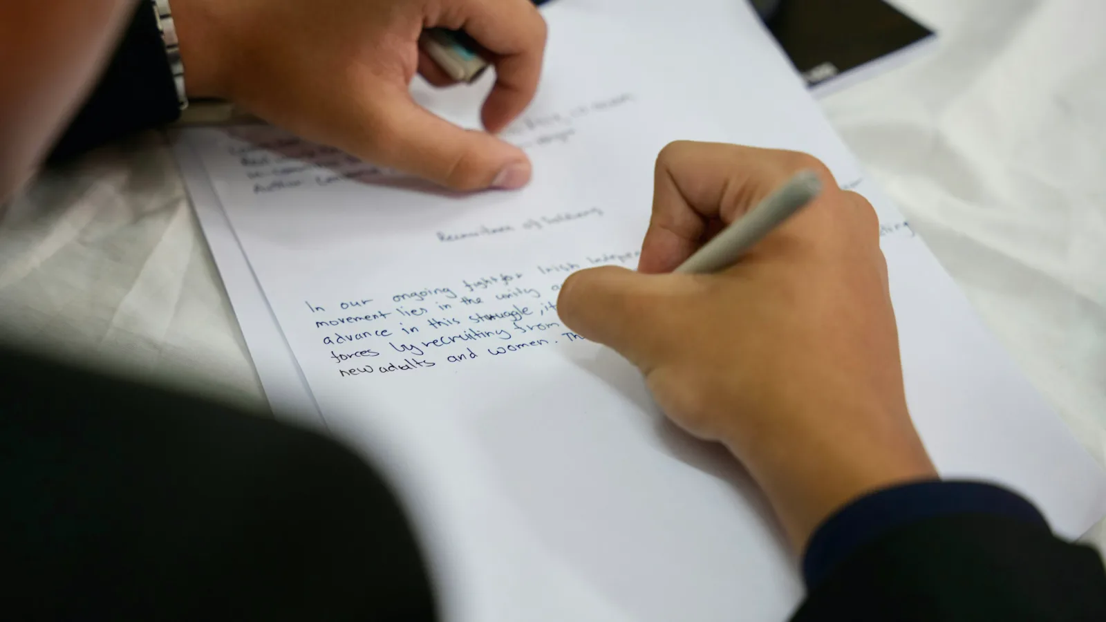 Eine Person füllt mit einem Stift ein Blatt Papier aus.